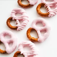 pink and brown donuts with frosting in the shape of o's on a white surface