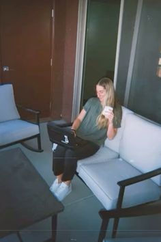 a woman sitting on a couch holding a coffee cup