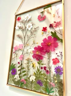 an art piece is hanging on the wall with flowers in it and butterflies flying around