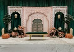 a stage set up for a wedding ceremony with flowers and pumpkins on the floor