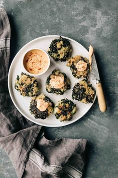 a white plate topped with broccoli and crab cakes next to a small bowl of dipping sauce