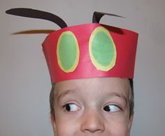 a young boy wearing a paper hat with scissors on it's head and eyes