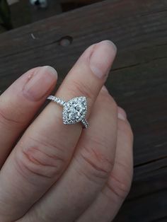 a woman's hand holding an engagement ring with a diamond in the shant