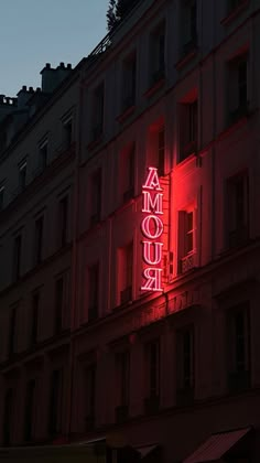 a red neon sign on the side of a building that says amour in french