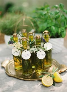 there are many bottles that have lemons and herbs in them on a tray with some leaves