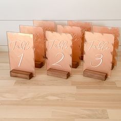 four wooden table numbers are displayed on a wood floor in front of a white wall