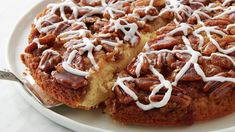 a cake with white frosting and pecans on top is sitting on a plate