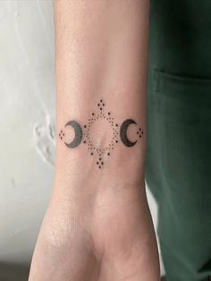 a woman's wrist tattoo with two crescents and stars in the middle of it