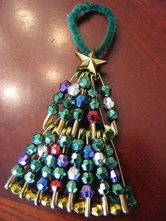 a christmas tree ornament hanging from a wooden table with beads and green cord