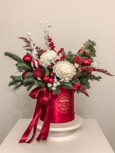 a red hat with white flowers and greenery in it on top of a table