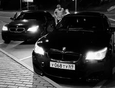 black and white photograph of two cars parked on the street