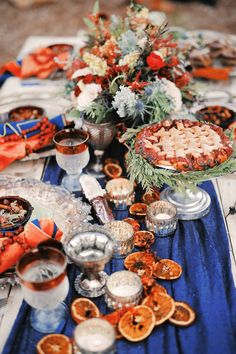 a table topped with lots of plates and bowls filled with food next to orange slices