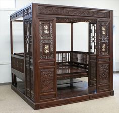 an ornate wooden bed frame with carvings on the top and bottom sides, in a room