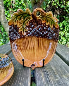 a ceramic bowl sitting on top of a wooden table next to a planter with leaves