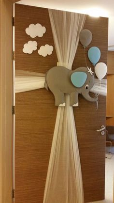 an elephant is hanging from the side of a door with balloons attached to its trunk