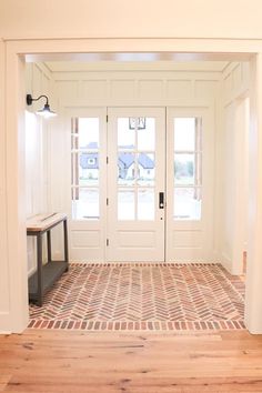 an empty entryway with two doors and a bench in the center, on a wooden floor