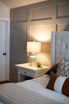 a white bed sitting next to a night stand with a lamp on top of it