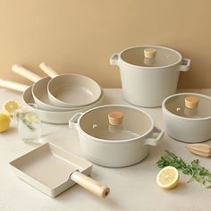 several pots and pans on a table with lemon slices, parmesan utensils and other kitchen accessories