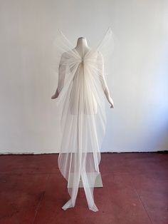 a white sculpture with sheer fabric draped over it