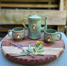 a tea set on a wooden tray with two cups and a flower in the middle