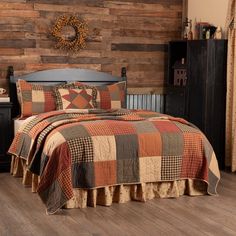 a bed with a brown and tan quilt on it's headboard next to a wooden wall