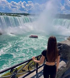 a woman is looking at the water as a boat passes by