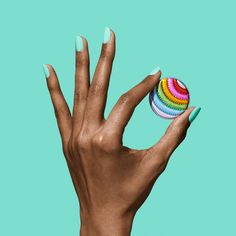 a woman's hand holding a multicolored ball on top of her finger