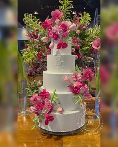 a three tiered white cake with pink flowers on top