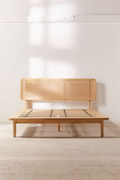 a wooden bench sitting in the middle of a room with white walls and flooring