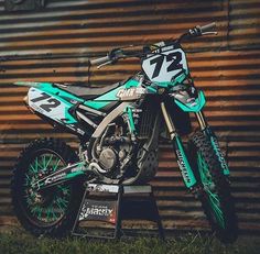 a dirt bike parked in front of a metal building with graffiti on it's side