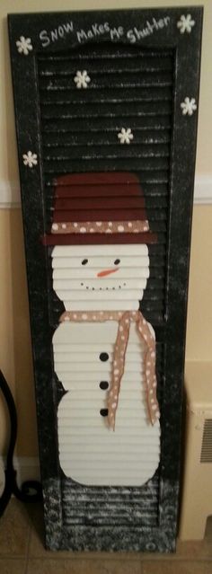 a snowman made out of shutters on the side of a door that is decorated