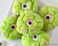 green monster cookies with googly eyes are on a white platter next to eyeballs