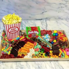 a tray filled with lots of candy and candies next to a cup of popcorn