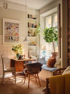 a living room filled with furniture next to a window covered in bookshelves and potted plants