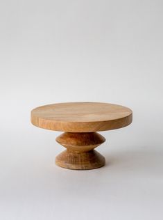 a round wooden table sitting on top of a white floor