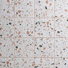 a white tile wall with brown and black speckles on the bottom, along with several different colored dots