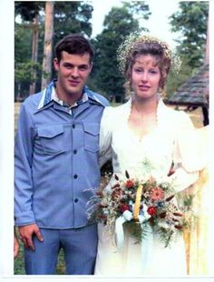 a man and woman standing next to each other in front of a field with trees