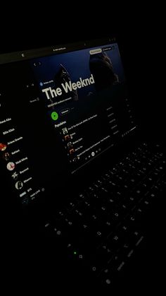 a laptop computer sitting on top of a black surface with the words the weekend written on it