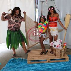 three women in costumes standing on a raft with a pig and other people behind them