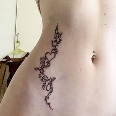 a woman's lower back tattoo with vines and hearts