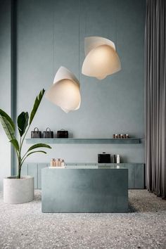 two lamps hanging from the ceiling above a counter in a room with gray walls and flooring