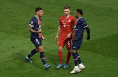 two soccer players are talking to each other while standing on the field in front of another player