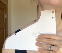 a woman holding up a piece of paper with the word shoulder cut off on it