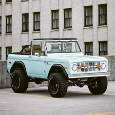 a light blue truck parked in front of a tall building