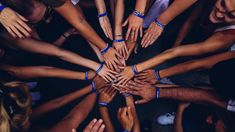 a group of people standing in a circle with their hands on top of each other