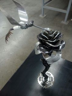 a metal sculpture made to look like a bird with wings flying over it's head