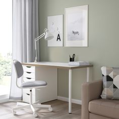 a desk with a chair, lamp and pictures on the wall above it in a living room