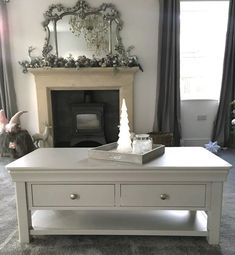 a living room with a white coffee table in front of a fire place and a mirror on the wall