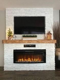 a fireplace with a flat screen tv mounted above it and lit candles on the mantle