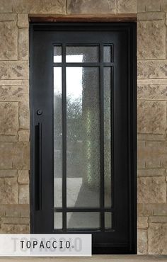 the front door is black and has glass panels on it, along with a brick wall